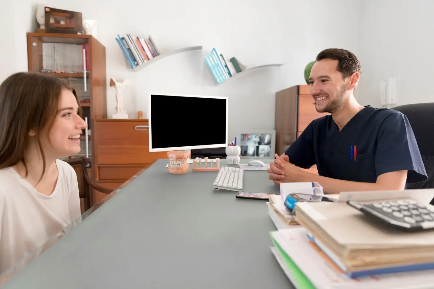 Glückliche/r Patient/in bei der Beratung mit einem männlichen Zahnarzt in einer Zahnklinik.